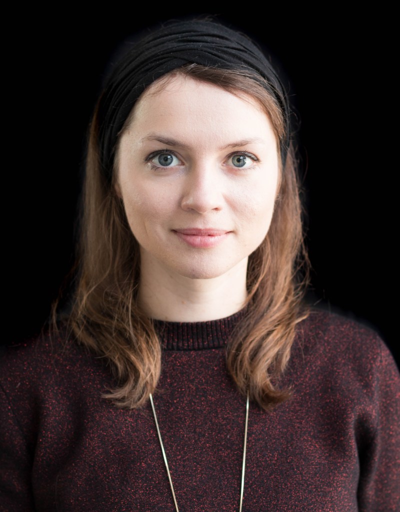 Frau mit braunen, schulterlangen Haaren, schwarzem Haarband und dunkelrotem Pullover - Profilausschnitt